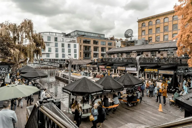 People at tables beside the water at Camden Market