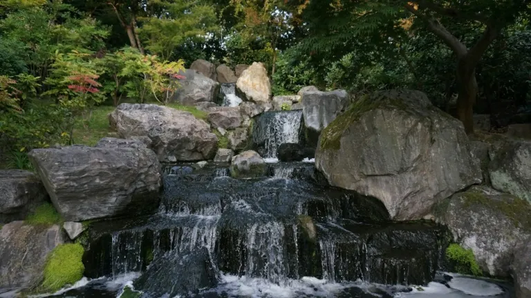 Small waterfall among rocks and trees in a Japanese-style garden