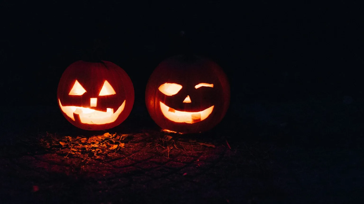 Two lit jack-o-lanterns glowing in the dark at night