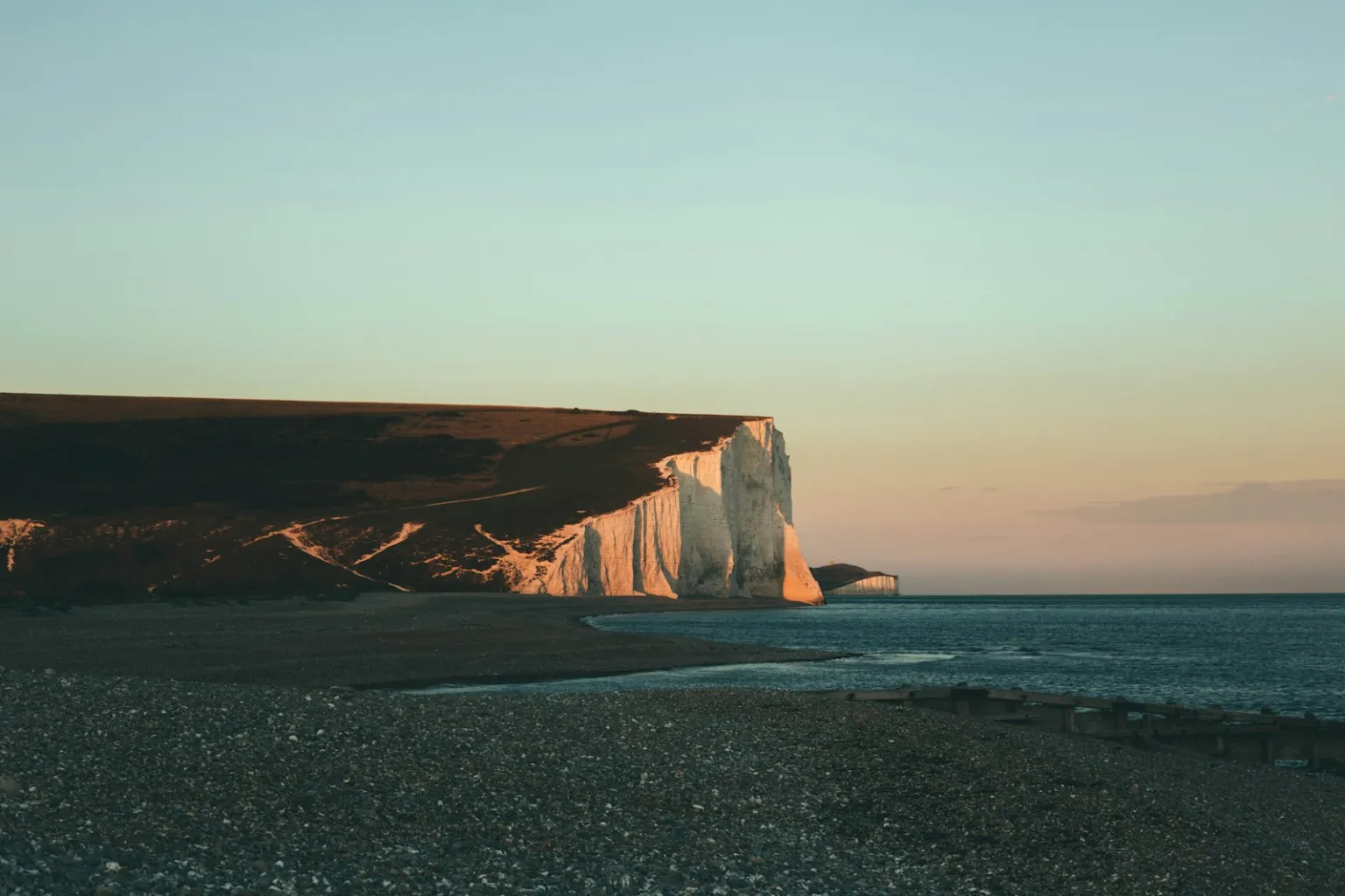 White chalk cliffs of the Seven Sisters at sunset above a shingle beach